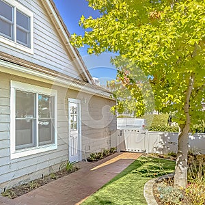 Square frame Facade of home with red brick pathway leading to the doors and arched gate