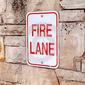 Square frame Fire Lane sign on stone retaining wall amid thick fresh snow on a hill in winter
