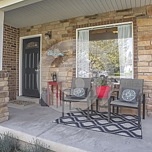 Square frame Furniture and Welcome wreath on the porch of home with red brick exterior wall