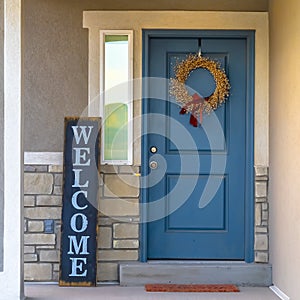 Square frame Golden wreath on the blue front door of a house with concrete and stone wall