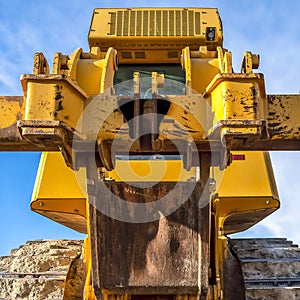 Square frame Heavy duty construction vehicle with peeling yellow paint and dirty metal tracks