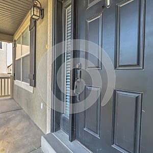 Square frame Home exterior view with gray front door sidelight and front porch on a sunny day