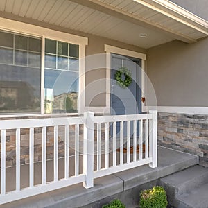 Square frame Home facade with small porch and blue gray front door with green leafy wreath