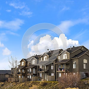 Square frame Houses with balconies and arched windows against blue sky with puffy clouds