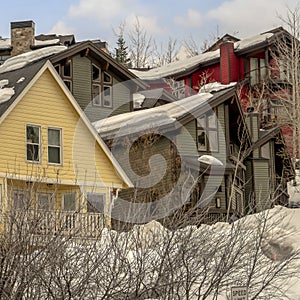 Square frame Houses on snow covered ground against blue sky with puffy clouds in winter