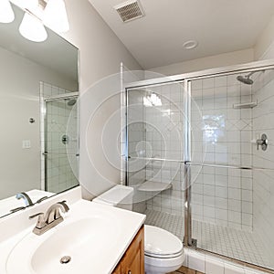 Square frame Interior of a bathroom with wooden vanity sink with tile counter and shower stall with glass