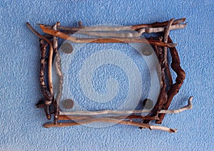 A square frame of larch cones and dry sticks on a blue background.