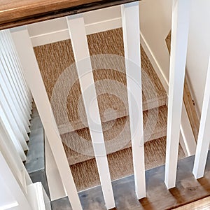 Square frame Looking down on U shaped indoor staircase with white baluster and brown handrail