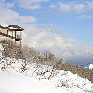 Square frame Mountainside home overlooking the valley and Wasatch Mountains under cloudy sky