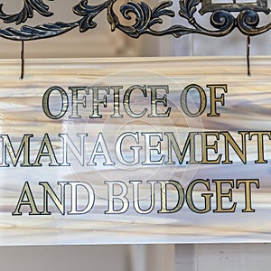 Square frame Office Of Management And Budget sign hanging on decrative wrought iron hanger photo