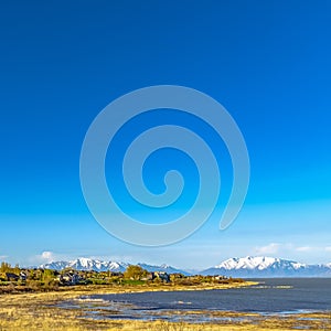 Square frame Panoramic view of a lake and snow covered mountain under deep blue sky