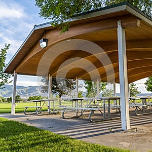 Square frame Picnic tables and benches under a pavilion on a scenic park on a sunny day