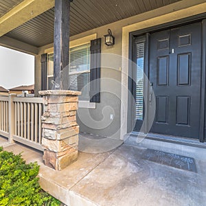 Square frame Pillars and railing on the porch of a home with gray front door and sidelights