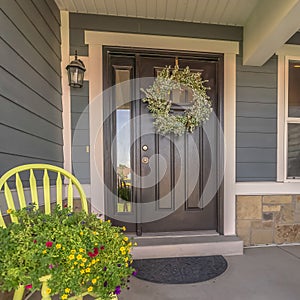 Square frame Porch and facade of home decorated with colorful flowers and wreath on the door