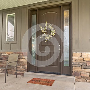 Square frame Porch and front door of a home with wood and stone brick wall sections