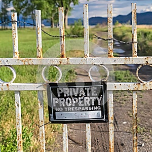 Square frame Private Property sign on an old rusty white gate locked with chain and padlock