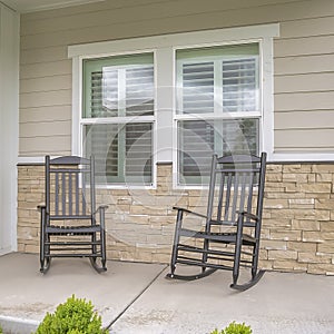 Square frame Rocking chairs against window at the porch of a home with wood and brick wall