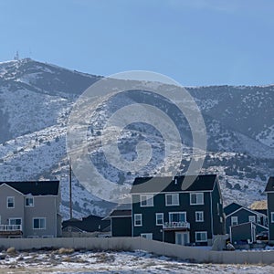 Square frame Row of houses against snow dusted hills and blue sky on a gloomy winter day