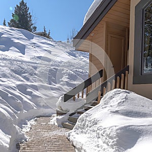 Square frame Stone brick pathway and stairs leading to home entrance amid deep layer of snow