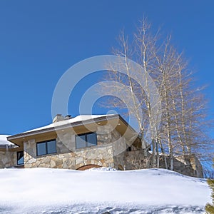 Square frame Stone home with snowy hip roof on a hill in Park City Utah viewed in winter