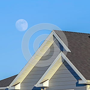 Square frame Sunlit home with dark pitched roof over horizontal gray wall siding and windows