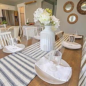 Square frame Table setting inside a dining room with brown table and white chairs photo