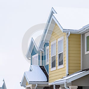 Square frame Townhome exterior with snowy gable valley roof against overcast sky in winter