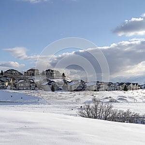 Square frame Wasatch Mountain in winter with houses on sunlit acres of snow covered terrain