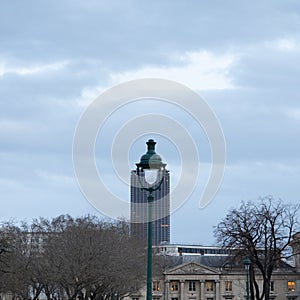 Square and funny view over a parisian street lamp with trees, Montparanasse tower and anciet buidlings