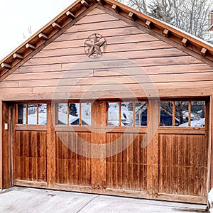 Square Garage exterior with snowy gable roof over glass paned door and wooden wall.