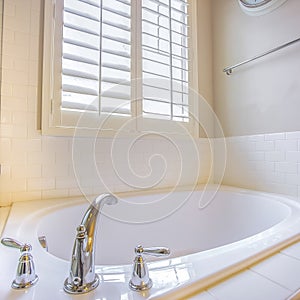 Square Gleaming built in bathtub and window with blinds inside a bathroom