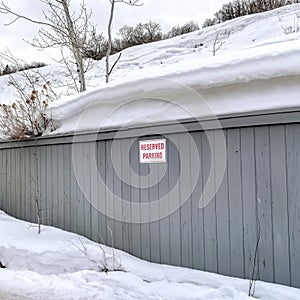 Square Gray wooden wall with Reserved Parking sign against snowy hill and sky in winter