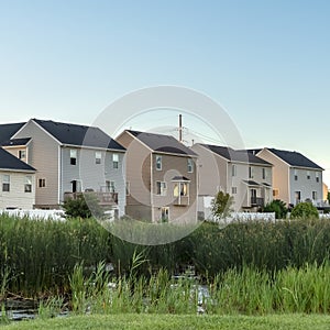 Square Green grasses and pond at a scenic park with houses and blue sky background photo