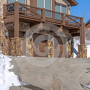 Square Home facade with three car garage amid snowy ground on a sunny winter day