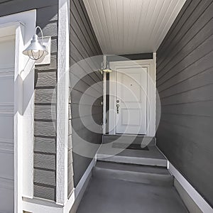 Square Home facade with view of the white front door and garage door on a sunny day