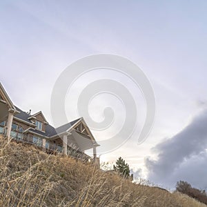 Square Home at neighborhood sitting on top of hill gainst snowy mountain and cloudy sky