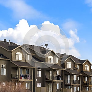 Square Houses with balconies and arched windows against blue sky with puffy clouds