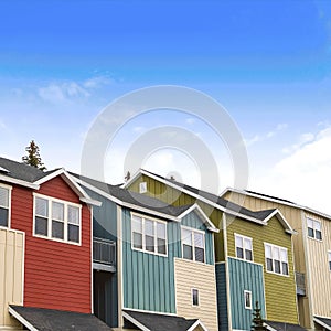 Square Houses with balconies and porches against blue sky and clouds on a sunny day