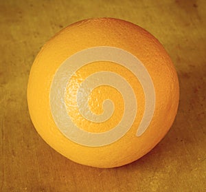 Square image of single whole orange fruit, uncut