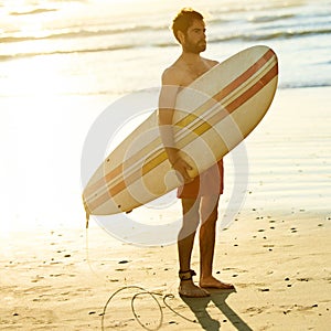 Square image of surfer holding a surfboard under his arm