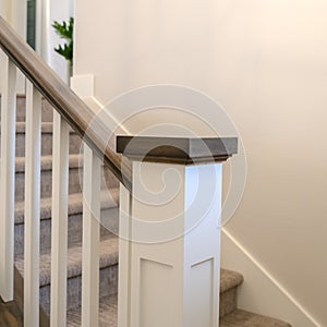 Square Indoor staircase of a home with white balusters brown handrail and newel