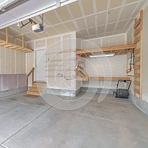 Square Interior of an unfinished garage with wooden shelving units and stairs to a white door