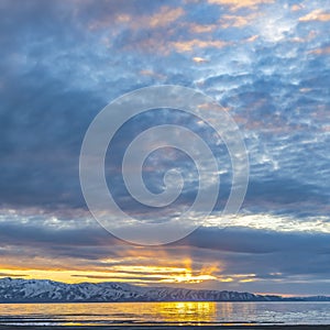 Square Lake and snow capped mountain underneath a sky filled with clouds at sunset