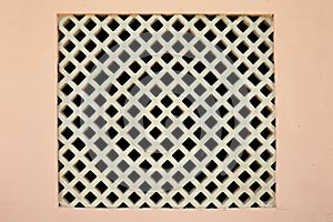 A square lattice window in the pink wall