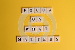 Square letters with text FOCUS ON WHAT MATTERS isolated on yellow background