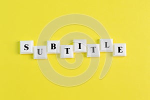 Square letters with text SUBTITLE isolated on a yellow background photo