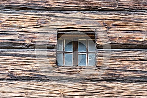 Square little window carved in an old, wooden surface or facade. Detail of tiny window on timber - made or timbered ed exterior