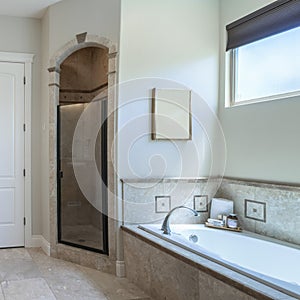 Square Master bathroom interior with antiqued limestone tiles