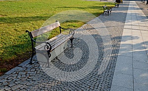 Square with metal benches in a row. the benches have spirally curled armrests. under the bench is an electrical switchboard with f