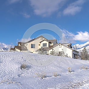 Square Mountain home with towering Wasatch peaks and cloudy blue sky background